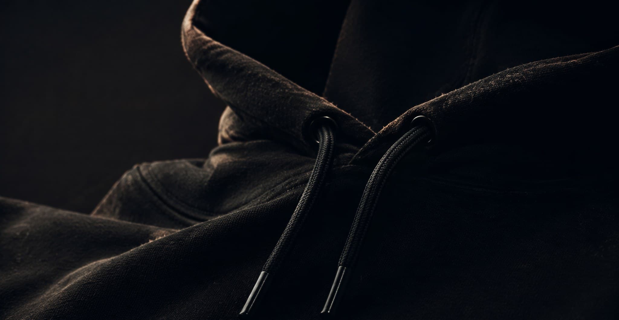 Macro photograph of the hood and drawstrings of a black heavyweight loopback terry hoodie